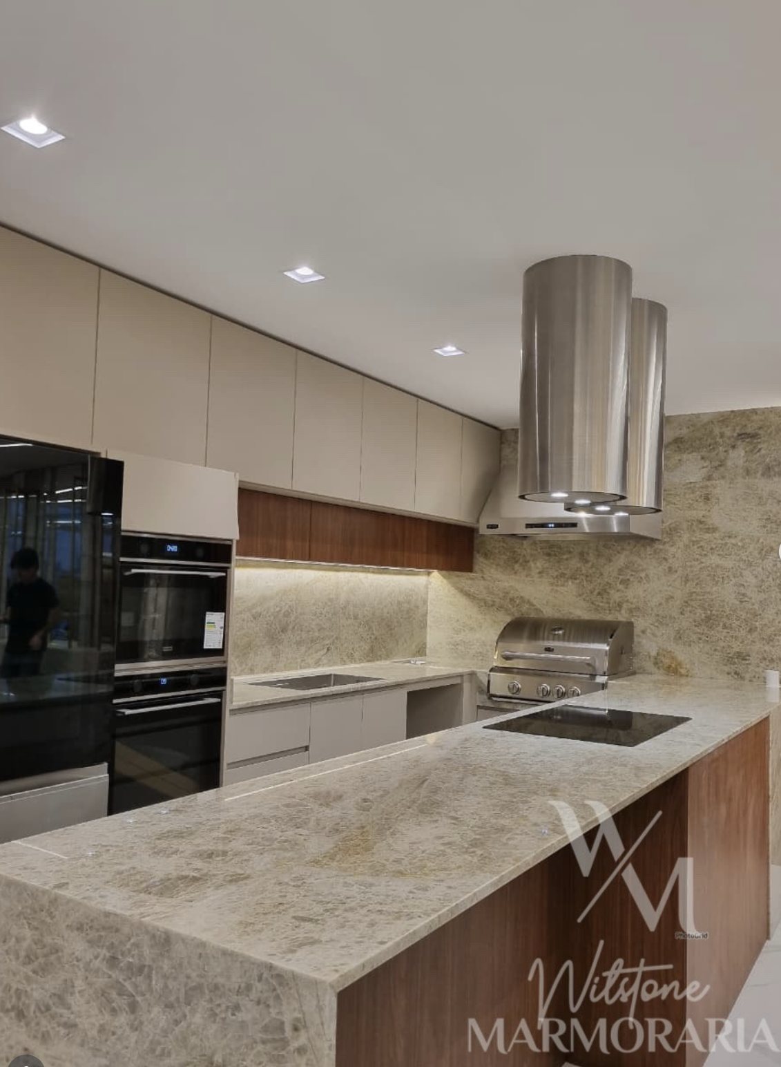 Cozinha com bancada e revestimento em pedra de veios marcados em tons claros